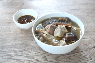 boiled fried grouper fish head and slice taro with black mushroom in soup on bowl dipping spicy chili soy sauce