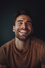 Portrait of a joyful young man with a beaming smile, exuding happiness and positivity on a dark background with space for text
