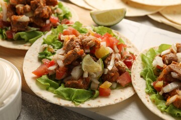 Delicious tacos with vegetables, meat and lime on table, closeup