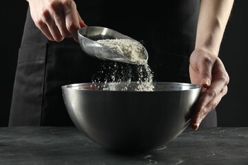 Making bread. Woman putting flour into bowl at grey textured table, closeup