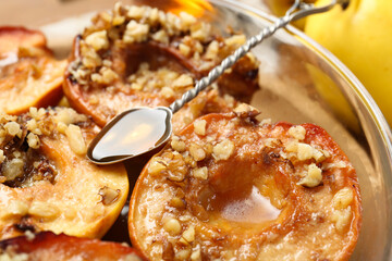Tasty baked quinces with walnuts and honey in bowl on table, closeup