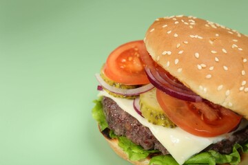 Burger with delicious patty on green background, closeup. Space for text