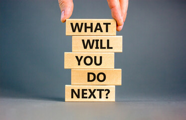 What will you do next symbol. Concept words What will you do next on wooden blocks. Beautiful grey table grey background. Businessman hand. Business, what will you do next concept. Copy space.