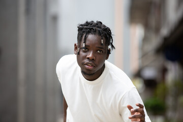 Portrait of young African American male showing short black hair braided hairstyle in the city...
