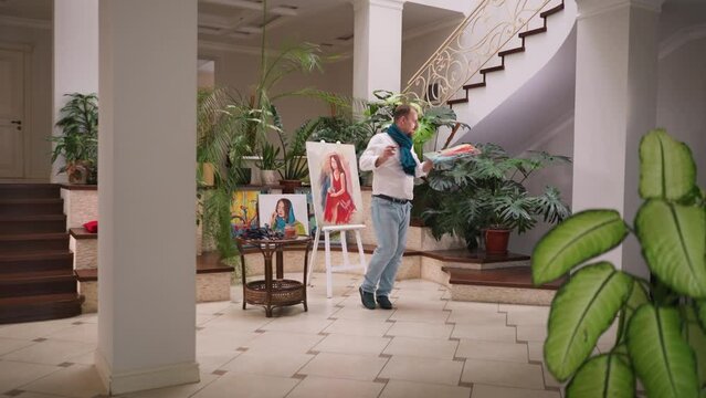 Artist dances in place during painting process. Professional painter lets rhythm guide brush strokes on canvas with lively and expressive dance. Creative inspiration