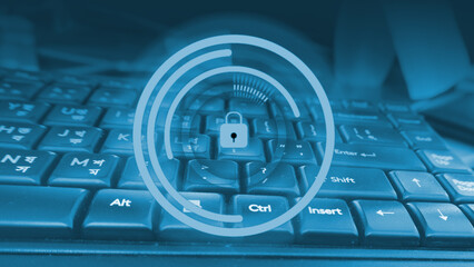 Conceptual image of cybersecurity with a padlock icon over a blue-toned keyboard technology...