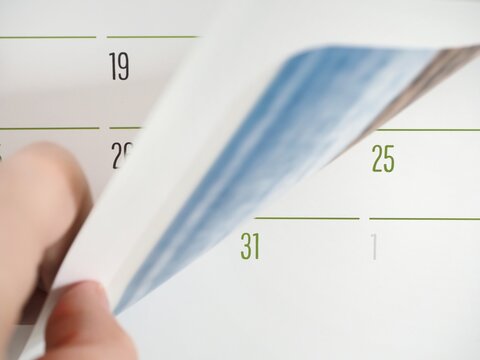 A hand changing month on a calendar