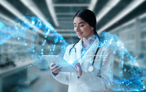 Smiling hindu woman doctor in white coat work on tablet