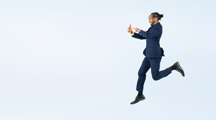 Full body photo of a black businessman jumping while looking at his smartphone. (We also sell PNGs that are cropped and have transparent background. Please search for "PNG" from the creator link.)