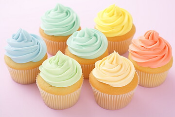 Multicolored muffins with whipped cream top isolated on pink background.