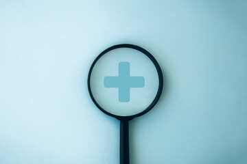 Health welfare, Health insurance concept. Magnifying glass with a plus sign on a blue background
