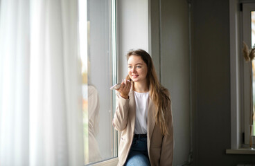 Fototapeta premium Work-life-balance, businesswoman on the windowsill in the hall of office with smartphone. Records a voice message