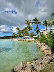 view of a small rocky cove of a caribbean resort with coconut trees and calm sea from a vacation day
