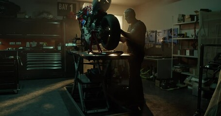 Male mechanic changing wheel of motorbike