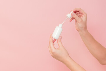 Hand holding glass cosmetic bottle for serum (hyaluronic acid and collagen) on pink background. Beauty concept