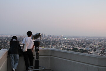 Los Angeles, California, USA; October 24 2023: Young couple watching Los Angeles skyline from the...