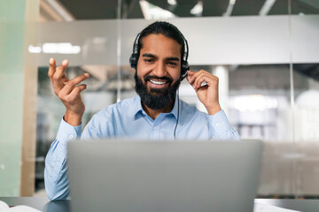 Friendly indian man office employee in headset having web call
