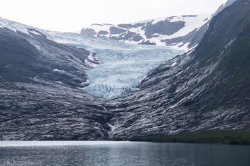 The Svartisen Glacier's icy cascade meets the calm waters, framed by the stark mountainous...