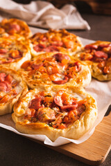 Fresh pizza pot pies with tomatoes, cheese and sausages on a wooden board vertical view