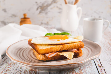 Croque madame sandwich with ham, cheese and egg on a plate on the table