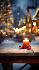 Red candle and Christmas ornaments on a snowy table with a blurred background of a Christmas market.