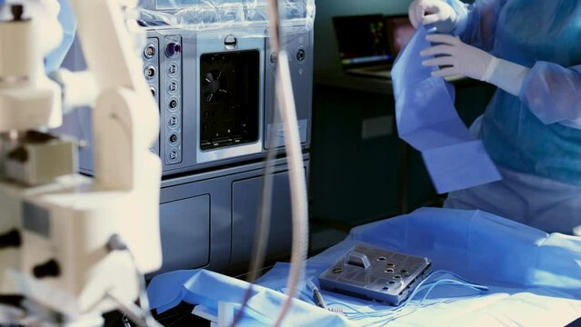 Doctors work in the operating room, installing a neuromicroscope. A medical team prepares equipment for neurosurgery. Vision correction, medical technologies, surgery.