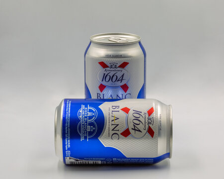 Kronenbourg Blanc 1664 wheat beer with citrus cans closeup on white.
