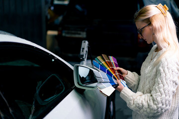 girls at the service station choose the paint color of white car on a color paper palette