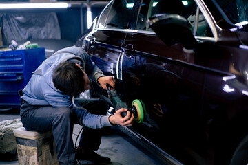 auto mechanic at service station doing final polishing until it shines