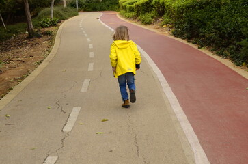 Fototapeta premium A child runs along the road. Empty asphalt road. boy running boy is walking in the park. Portrait of a cute child.