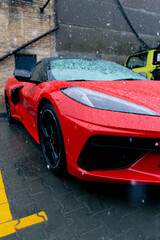 close-up of the side of red sports car standing on the street wet after snow