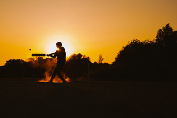 Silhouette of a person playing cricket in a sunset
