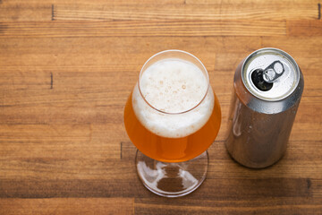 Craft beer glass next to open can on wooden table - obrazy, fototapety, plakaty