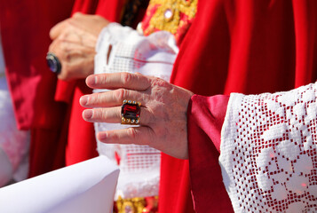 hand of the cardinal with a showy cassock ring with red ruby during the blessing of the faithful at the end of the mass - obrazy, fototapety, plakaty