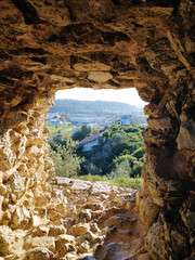 View through the window of an ancient stone tower onto a natural landscape.