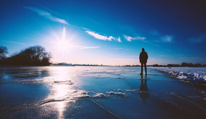 Man standing on a frozen lake in winter, looking at the horizon