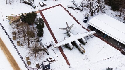 Snow-covered tanks, artillery, armored vehicles, military vehicles, and airplanes in Poznan Citadel during winter, captured by drone.