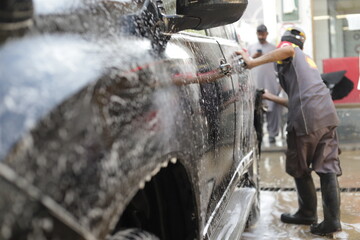 close up of black SUV car headlight cleaning and washing at car wash service station, soap foam on black SUV car