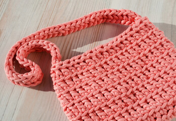 Small women's bag made of cotton cord. Pink handbag on a light background.