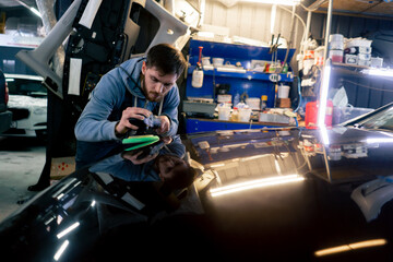 the car mechanic at a service station doing the final polishing to shine - obrazy, fototapety, plakaty