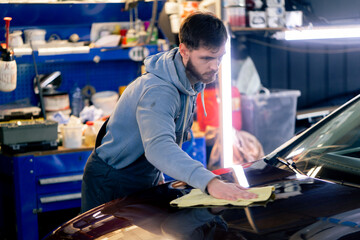 the car mechanic at a service station doing the final polishing to shine