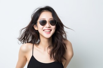 Cheerful young woman in a black top with fashionable round sunglasses, joyful pose.