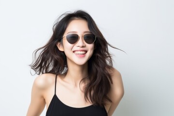 Naklejka premium Cheerful young woman in a black top with fashionable round sunglasses, joyful pose.