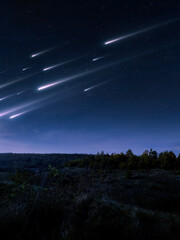 Bolides in the night sky. A stream of meteors illuminates the starry sky. Fabulous night landscape. Bright shooting stars.