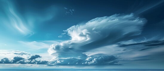Dramatic large cloud hovering over vast and peaceful field under clear blue sky - obrazy, fototapety, plakaty
