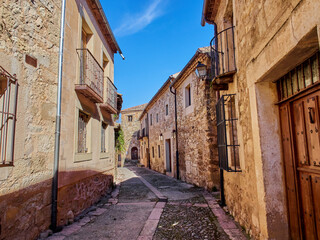 Fototapeta na wymiar Cobblestone street with stone houses in Pedraza, a medieval walled village in the province of Segovia. Castilla y León, Spain, Europe