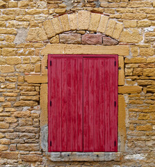 Old closed wood window shutters on a wall of golden stones (aka Couzon stones) in Beaujolais, France