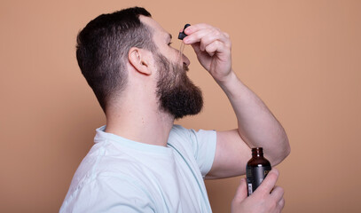 Closeup of male face and pipette with a oil for a beard growth.
