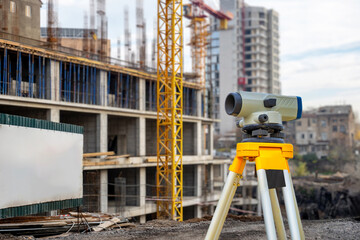 Geodetic instrument. Building under construction. Optical theodolite. Geodetic device on tripod. Construction site without anyone. Equipment for surveyor. Geodetic quality control of construction