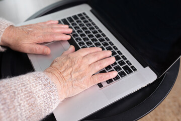 Mature female hands typing text on keyboard, senior elderly business woman working on laptop...